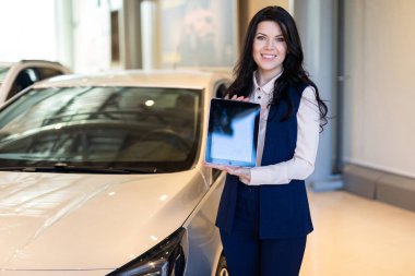 Arabanın yakınında duran ve bir tablet tutan şık sigorta ajanı