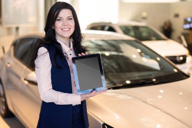 Arabanın yakınında duran ve bir tablet tutan şık sigorta ajanı