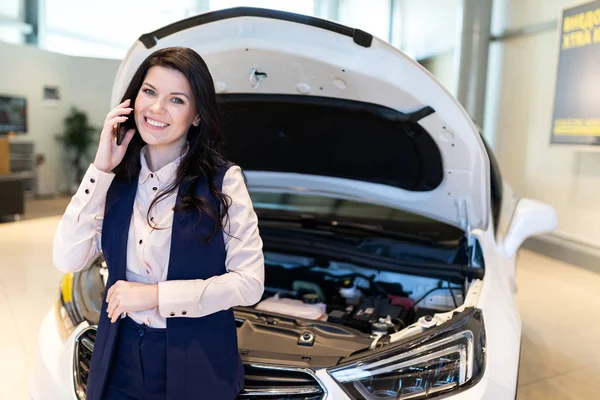 Güzel satış-yemlik yeni araba incelemek ve bayilik showroom telefonla konuşuyor