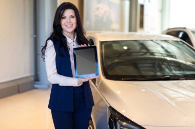 Arabanın yakınında duran ve bir tablet tutan şık sigorta ajanı