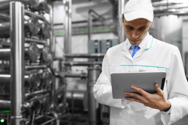Gri tablet ile süt fabrikasının üretim bölümünde duran beyaz cüppe ve bir kap adam portresi