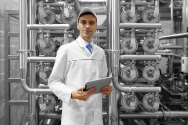Gri tablet ile süt fabrikasının üretim bölümünde duran beyaz cüppe ve bir kap adam portresi