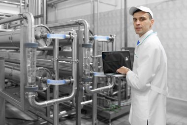 Gri tablet ile süt fabrikasının üretim bölümünde duran beyaz cüppe ve bir kap adam portresi