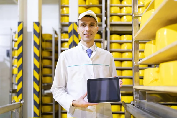 Retrato del hombre con una bata blanca y una gorra de pie en el departamento de producción de la fábrica de lácteos con tabletas grises —  Fotos de Stock
