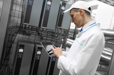 Gri tablet ile süt fabrikasının üretim bölümünde duran beyaz cüppe ve bir kap adam portresi