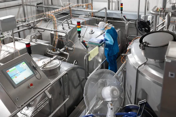 Arbeiter in blauem Gewand und Mütze inspizieren die Produktionsabteilung der Molkerei — Stockfoto