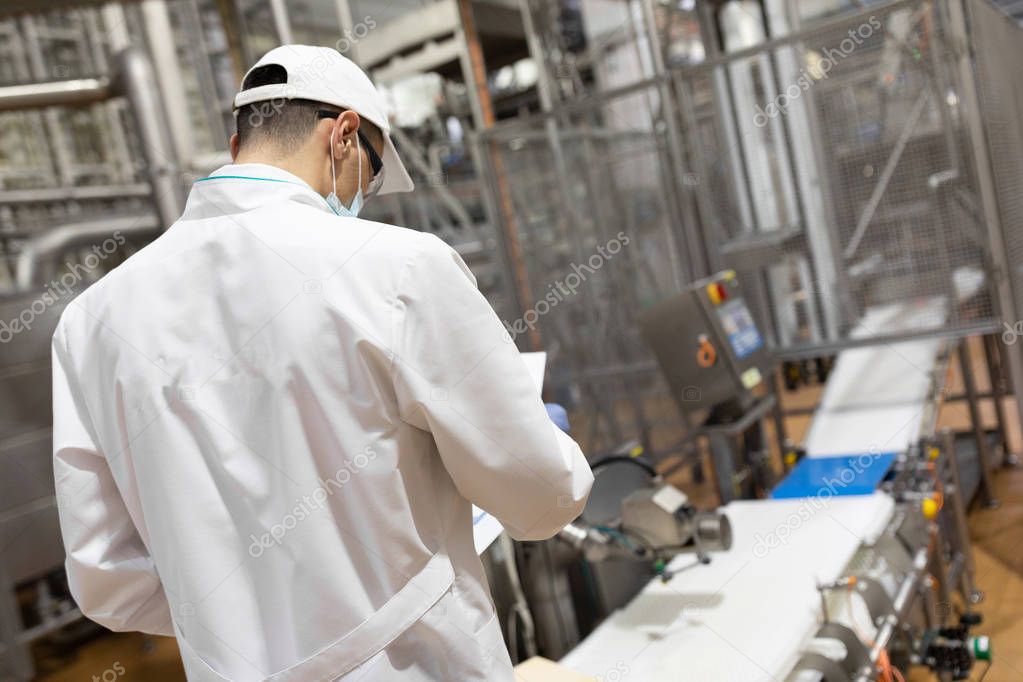 man in a white robe and a cap make an inspection of the production line