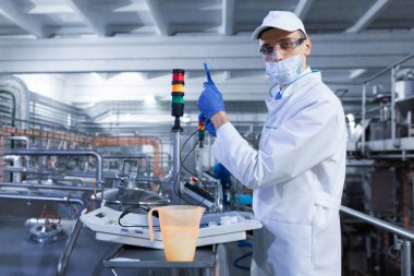 beyaz bir cüppe ve bir kap adam üretim hattı bir denetim yapmak