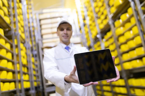 Retrato del hombre con una bata blanca y una gorra de pie en el departamento de producción de la fábrica de lácteos con tabletas grises —  Fotos de Stock