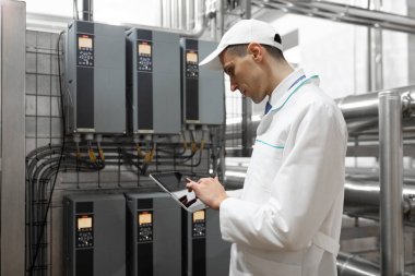 Gri tablet ile süt fabrikasının üretim bölümünde duran beyaz cüppe ve bir kap adam portresi