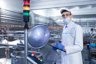 Bir maske ve bir scrub müfettiş elinde bir klasör-tablet ile süt fabrikasında duruyor