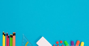 Yarı görünür çok renkli kalemler, üçgen cetvel, beyaz çizik kağıt yığını, kırmızı pushpins bir grup Panorama, dört renkli vurgulayıcılar izole soluk mavi bir yüzey yalan