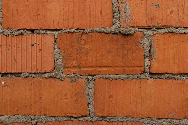 Eine schäbige rote Ziegelmauer mit Mörtel im Hintergrund — Stockfoto