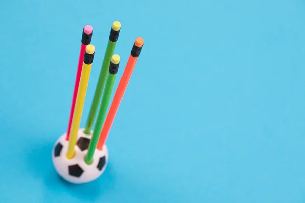 Круглий футбольний м'яч форми олівця чашка з п'ятьма барвистими олівцями в ньому на блакитній поверхні ізольовані — стокове фото