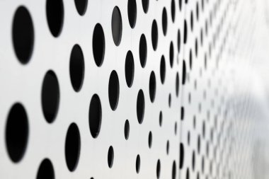 Beyaz arka planda hızlı siyah büyük nokta deseni, delikli metal panel yüzeyinde yuvarlak delikler dokusu, açı görünümü