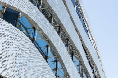 Gökyüzü arka planda yuvarlak delikleri ile metal delikli panel ile yüksek modern bina inşaat düşük açı görünümü