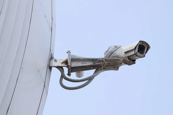 Modern old CCTV camera on a white wall or tiled building edge. Sky background. Concept of surveillance and monitoring. — Stock Photo, Image