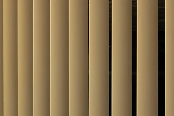 Bézs vagy arany 3D csíkok a fekete háttér. A Louvre redőnyök, mint a minta. — Stock Fotó