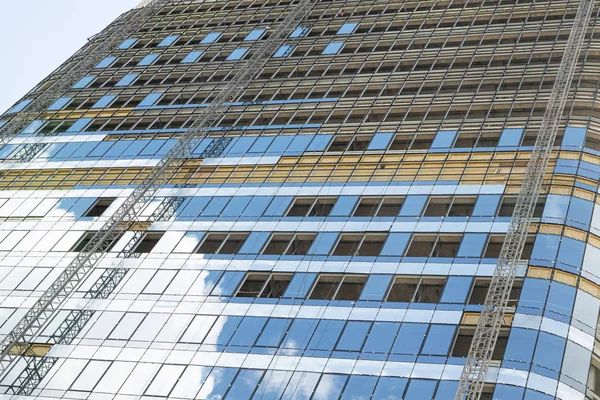 Низкий угол обзора современного здания из стекла в процессе реконструкции с отражением неба на его окнах . — стоковое фото