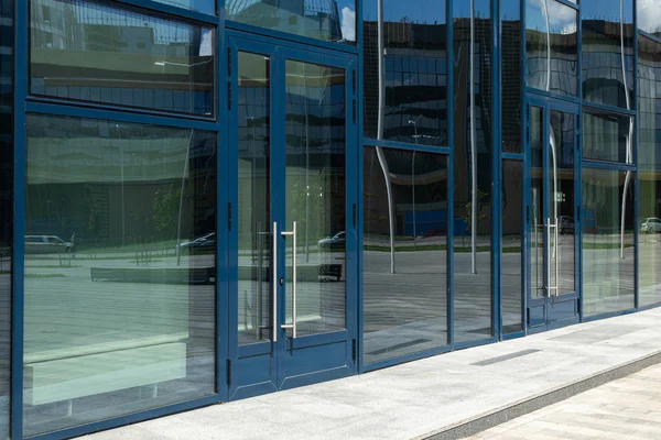 Diagonal view of modern building wall with bif glass window and door with blue frame. Street reflection. — Stock Photo, Image