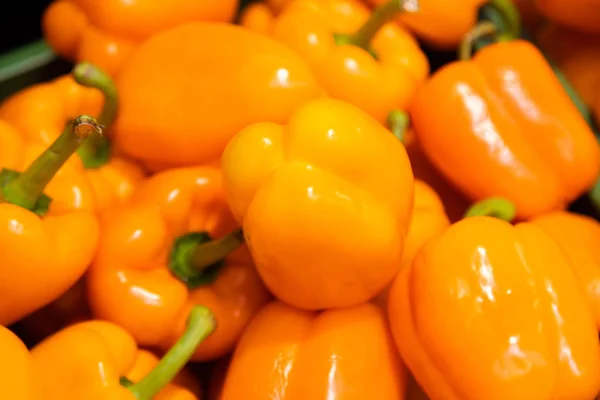 Orange sweet bell peppers as background at shop or street market. — Stock Photo, Image