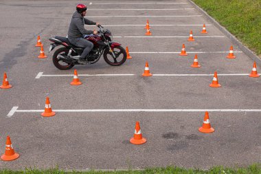 Minsk, Beyaz Rusya - Haziran, 2019.Turuncu trafik konileri arasında park alanında motor-bisiklet üzerinde kask man