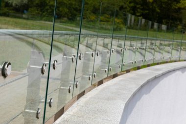 Innovative crescent glass fencing at sport arena or park road. clipart