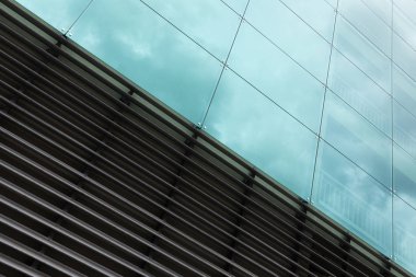 Gökyüzü yansıması ile modern duvar yüzeyi, cam ve metal doku diyagonal görünümü.