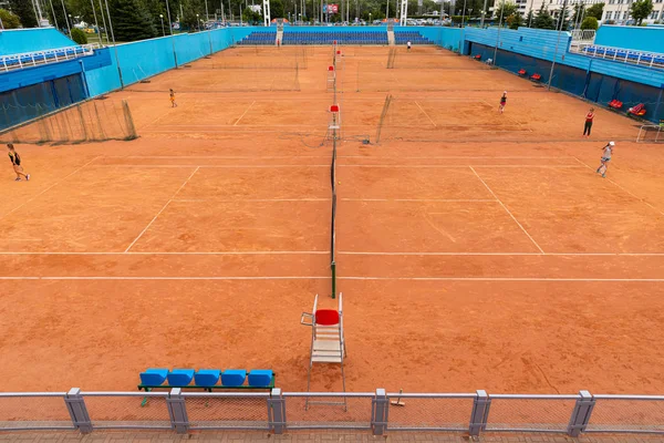 Birçok kişi, kırmızı homurdanan tenis kortunda tenis oynayan çocuklar — Stok fotoğraf