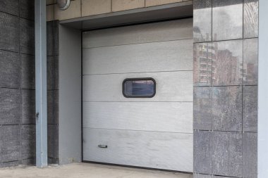 Beyaz panel kapılı kiremitli duvarda kapının diyagonal görünümü