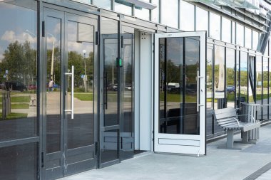 Üzerinde sokak yansıması ve yakındaki bir bank ile cam duvarlar ve kapılar ile parlak cephe bina iş veya daire giriş