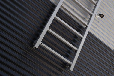 Siyah beyaz oluklu duvar kavşağına karşı metal merdiven ve gözetim kamerası yakın çekim