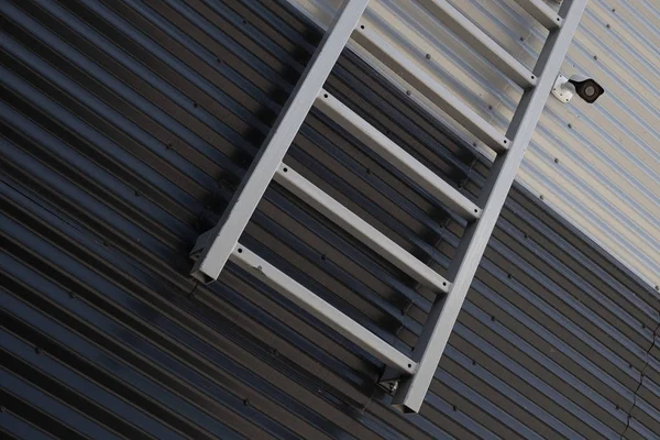 Primer plano de la escalera de metal y la cámara de vigilancia contra la unión de la pared ondulada en blanco y negro —  Fotos de Stock