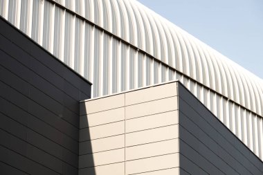 Metal duvarlar ve açık gri renk kemerli çatı ile binanın dış görünümü