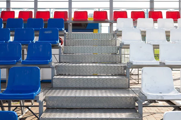 Front view of blue and red plactic seats on sport stadiums grandstand with metal steps — Stock Photo, Image