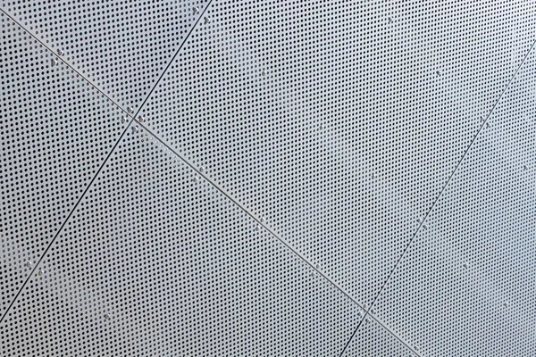 Close-up de superfície de metal branco com um monte de pequenas aberturas redondas — Fotografia de Stock