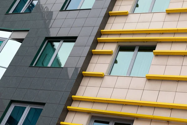 Cutting-edge tiled luxury apartment facade with beige and black ceramics, bright yellow details and wide windows