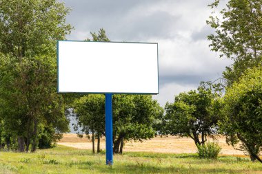Karayolu boyunca ağaçlı alana karşı kocaman boş reklam panosu.