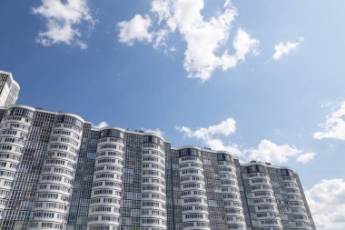 Beyaz bulutlu mavi gökyüzüne karşı duvarları şişkin bir apartman.
