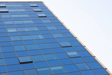 Bina duvarının mavi camdan yüzeyi mavi gökyüzünü yansıtıyor. Çok az pencere açılır