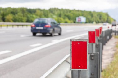 Kırmızı yansıtıcı elementli işaret direklerine yakın çekim. Alanın derinliğine sahip fotoğraf