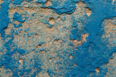 Üzerinde mavi boya lekeleri olan kaba bir duvar.