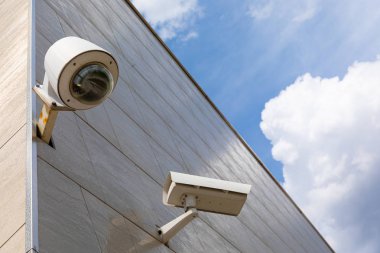 Güvenlik kamerası aygıtı ve lamba seramikli gri bina duvarı bulutlu gökyüzü arkaplanı, düşük açı görünümü