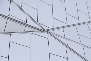Geometrik olarak tasarlanmış beyaz duvardaki metal çizgilerin birleştiği yere yakın plan.