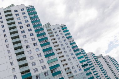 Beyaz renkli ve yeşil balkonlu bir apartman dairesi gri gökyüzü arkaplan şehir manzarasına yavaş yavaş iniyor.