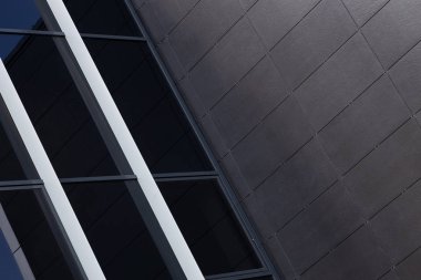 Siyah cam duvara yakın çekim ve düz olmayan karolarla kaplı siyah duvar.