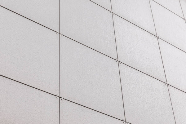 Diagonal close-up of light gray smooth tile on wall surface.