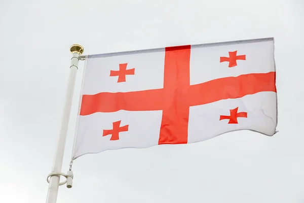 Georgian flag waving in the clouds against white sky