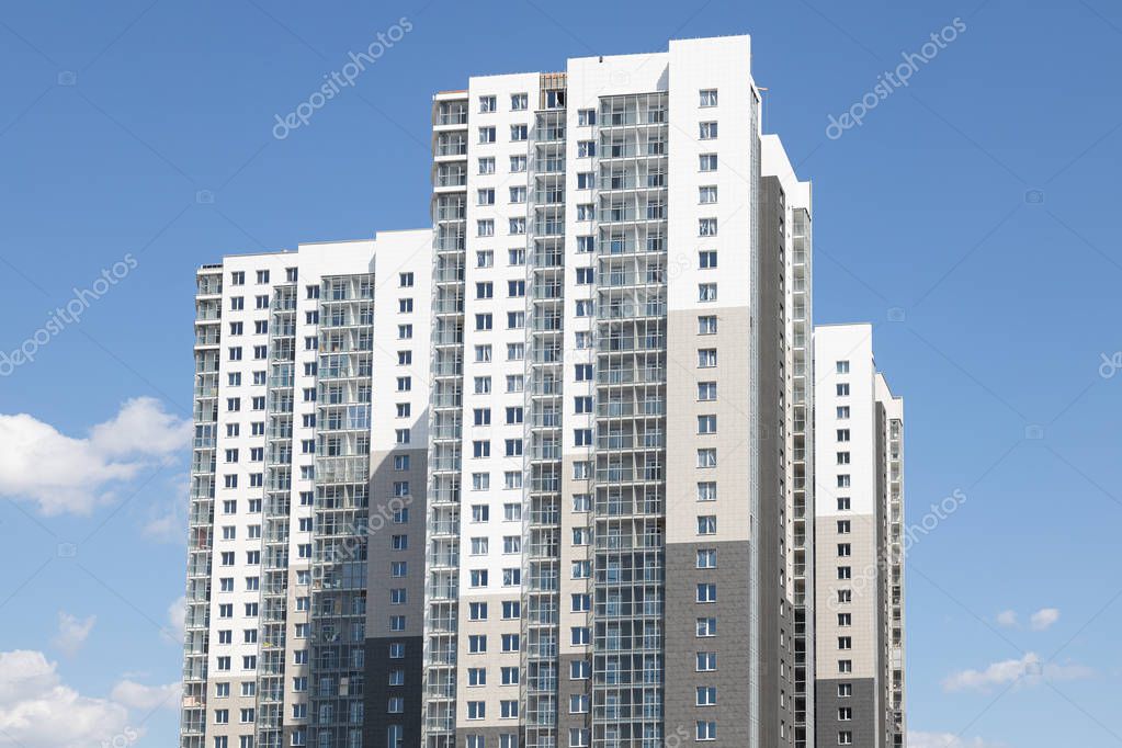 High white-grey multi-family dwelling building against blue sky in daylight