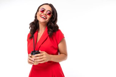 Kırmızı tulumlu ve güneş gözlüklü güzel esmer kız kahve içiyor.